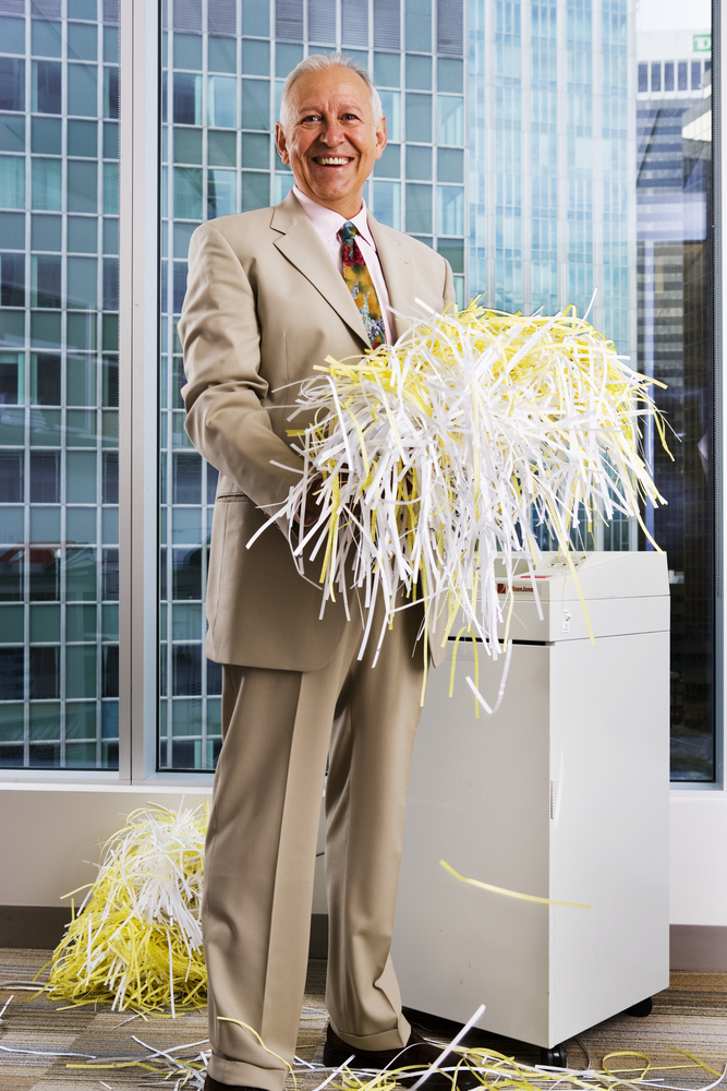 A businessman holding shredded paper in his office