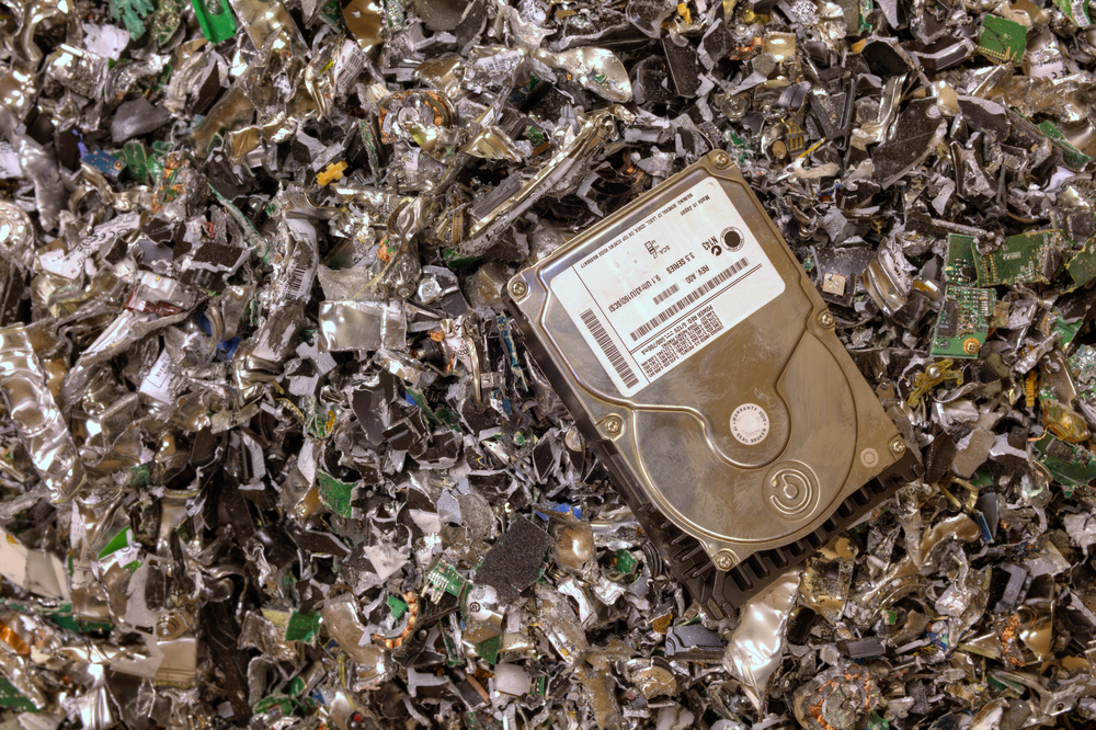 An intact hard drive resting on a pile of shredded hard drives.