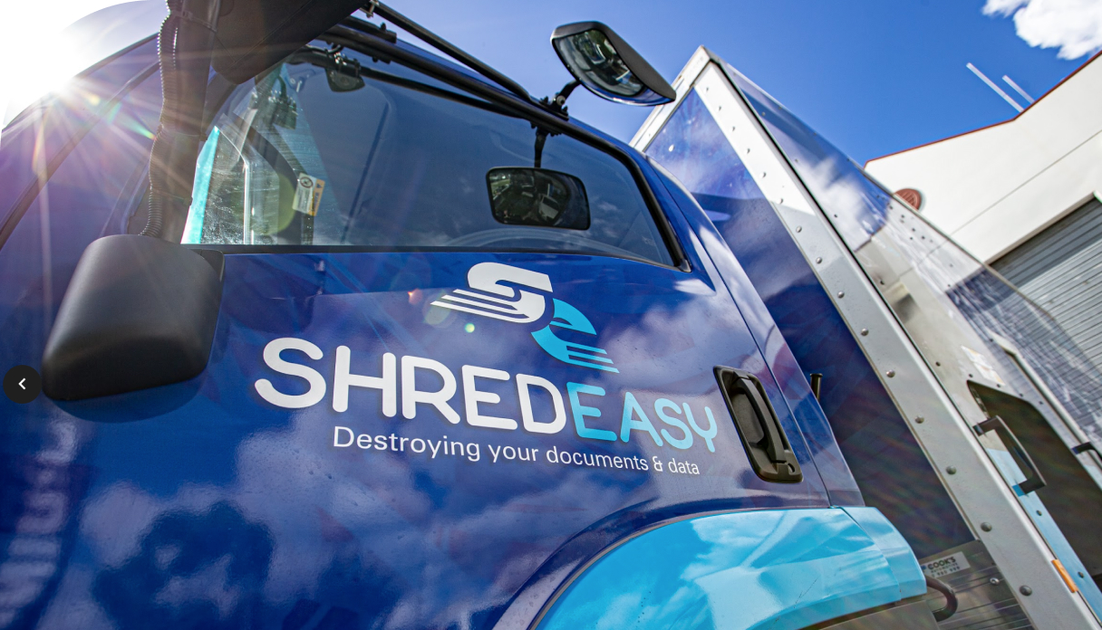 Side view of Shred Easy blue truck with logo and tagline for shredding services