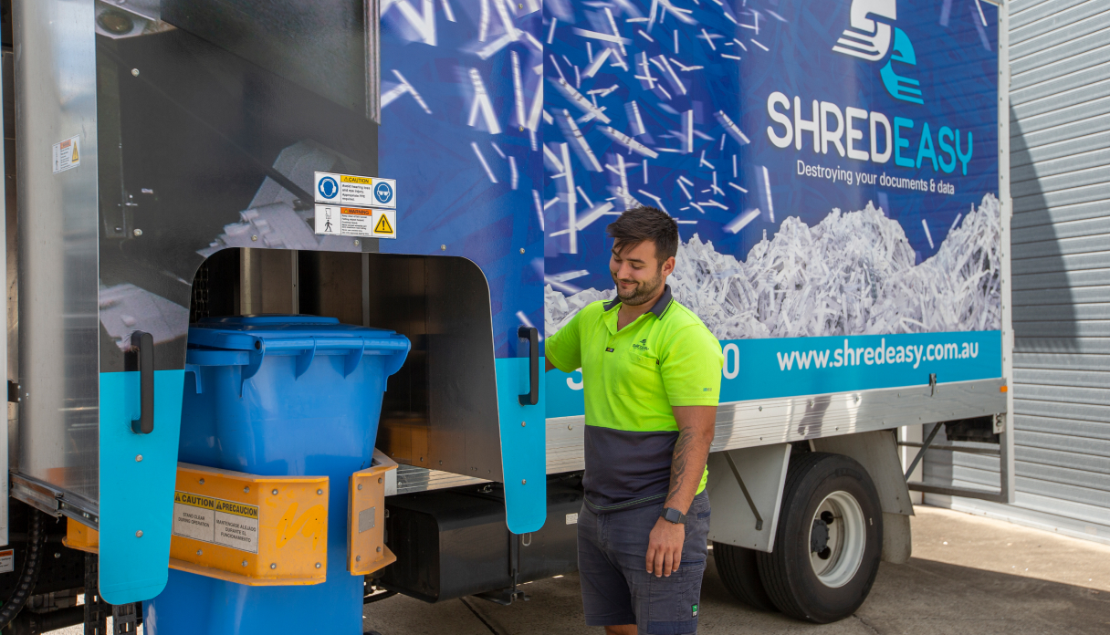 Worker operating Shred Easy truck shredding bin for secure document disposal